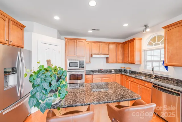 a kitchen with stainless steel appliances granite countertop a stove a sink and a microwave