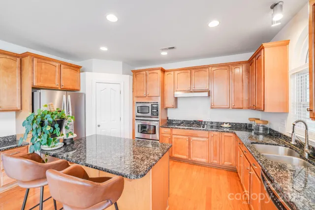 a kitchen with stainless steel appliances granite countertop sink stove and large window