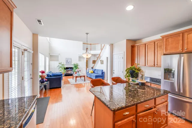 a kitchen with stainless steel appliances granite countertop a refrigerator a stove and white cabinets with wooden floor