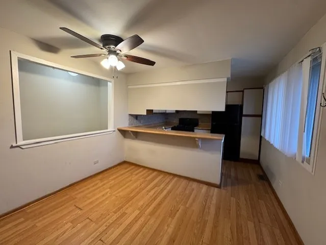 a kitchen with a wooden floor and a ceiling fan