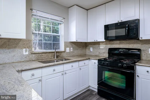 a kitchen with granite countertop white cabinets stainless steel appliances and a sink