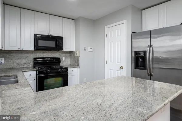 a kitchen with granite countertop a refrigerator and a stove top oven