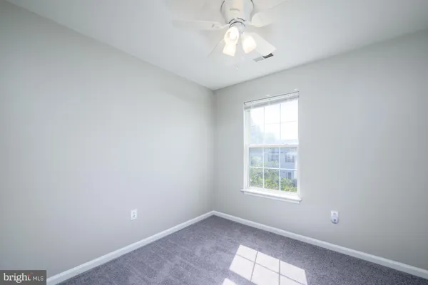 an empty room with a window and chandelier fan