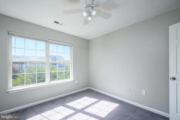 an empty room with a window and chandelier fan