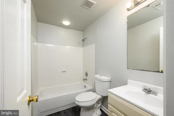 a bathroom with a bathtub shower sink mirror vanity and toilet