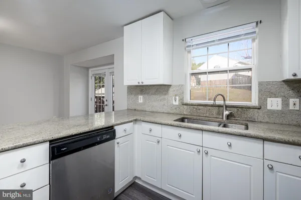 a kitchen with granite countertop white cabinets and a window