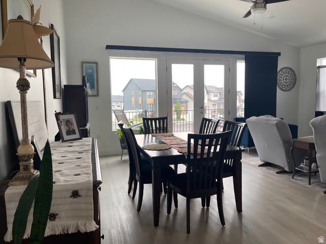 655 Oliver Road Tooele, UT 84074 - Photo 5 of 21 Bright dining area featuring a black wood dining table with seating for six, hardwood flooring throughout, and expansive multi-panel french doors and windows providing natural light and outdoor deck access