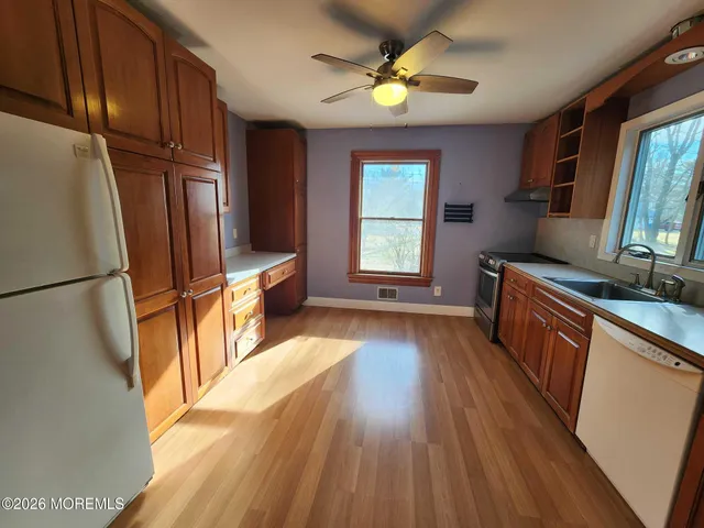 a kitchen with stainless steel appliances granite countertop a refrigerator a stove top oven a sink dishwasher and wooden floor