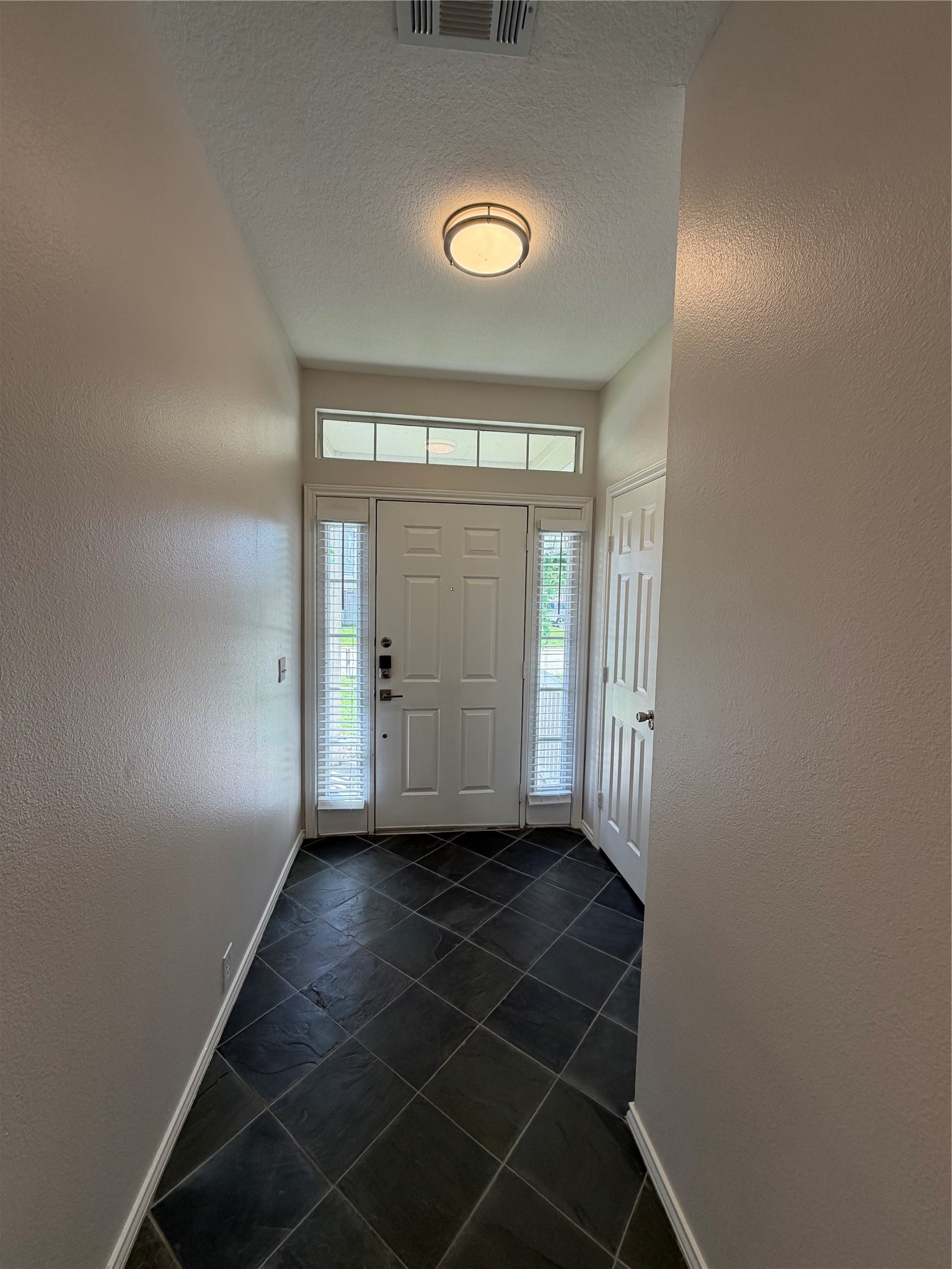 2123 Rustling Trees Way Spring, TX 77373 - Photo 10 of 21 This photo shows a well-lit entryway featuring a modern light fixture, tile flooring, and a front door flanked by narrow windows, allowing natural light to enhance the space.