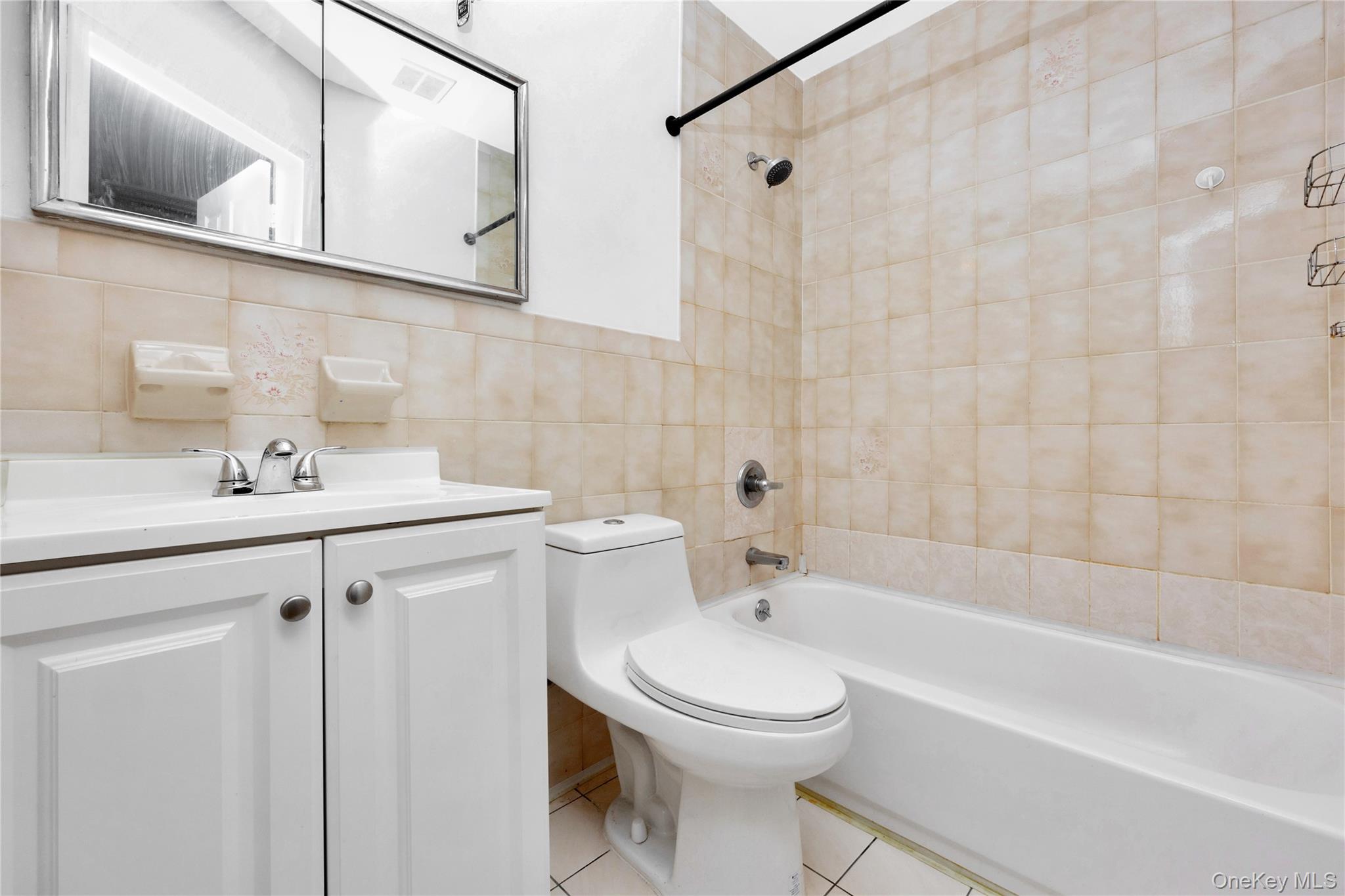 41-23 76th Street, Unit 2B Queens, NY 11373 - Photo 6 of 8 Bathroom featuring vanity, shower / washtub combination, tile walls, tile patterned floors, and tasteful ceramic tiles