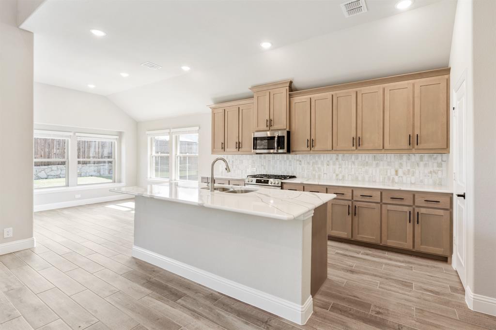 2016 Dundalk Lane Forney, TX 75126 - Photo 11 of 40 a kitchen with kitchen island granite countertop a sink cabinets and wooden floor