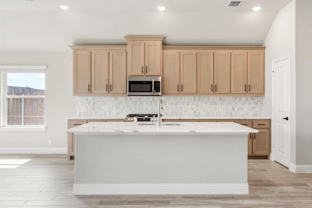 2016 Dundalk Lane Forney, TX 75126 - Photo 12 of 40 a kitchen with stainless steel appliances granite countertop a stove a sink and a microwave