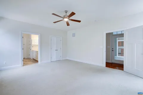an empty room with a ceiling fan and windows