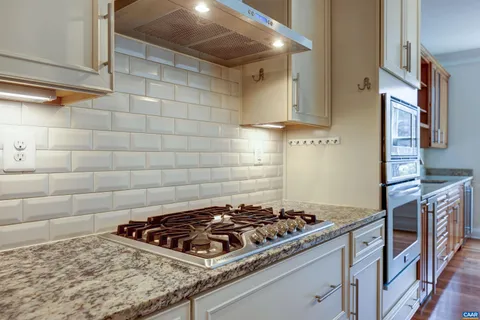 a kitchen with kitchen island granite countertop a sink cabinets and stainless steel appliances