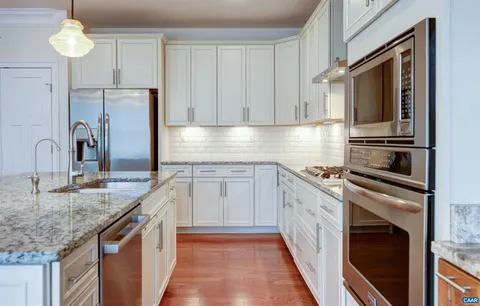 a kitchen with granite countertop stainless steel appliances stove top oven and cabinets