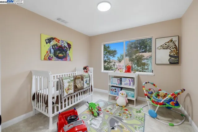 a bedroom with furniture a baby crib and a painting on the wall