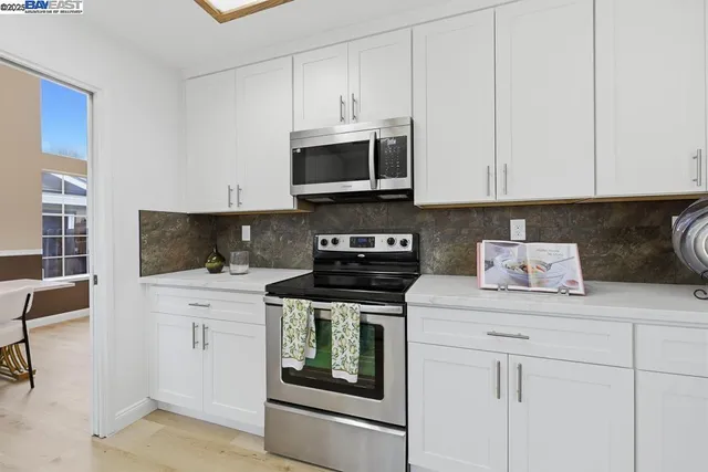 a kitchen with stainless steel appliances granite countertop a stove a sink and a microwave