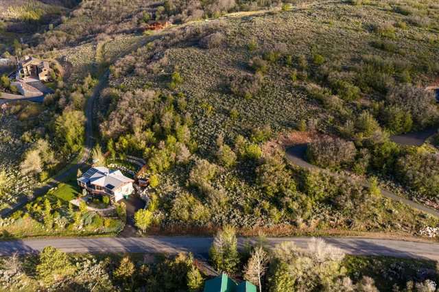 6975 North Durfee Way, Unit 20 Eden, UT 84310 - Photo 2 of 15 Hillside residence featuring a large deck, mature trees, and a paved driveway