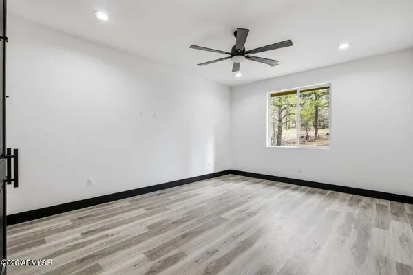an empty room with wooden floor fan and windows