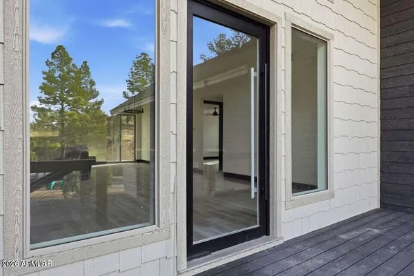 a view of a room with wooden floor white walls and windows