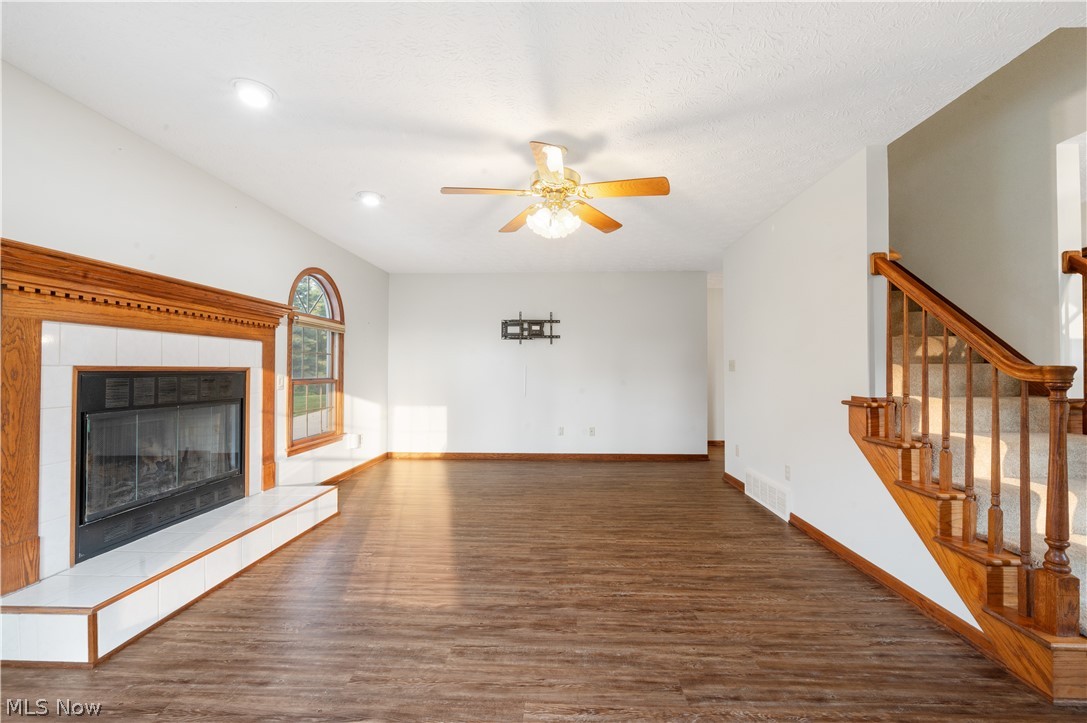 1239 Congress Lake Road Mogadore, OH 44260 - Photo 12 of 35 Unfurnished living room with a tile fireplace, ceiling fan, and dark hardwood / wood-style floors