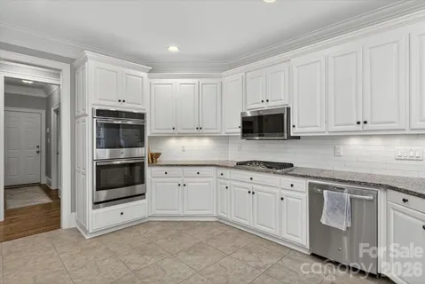 a kitchen with granite countertop white cabinets and stainless steel appliances