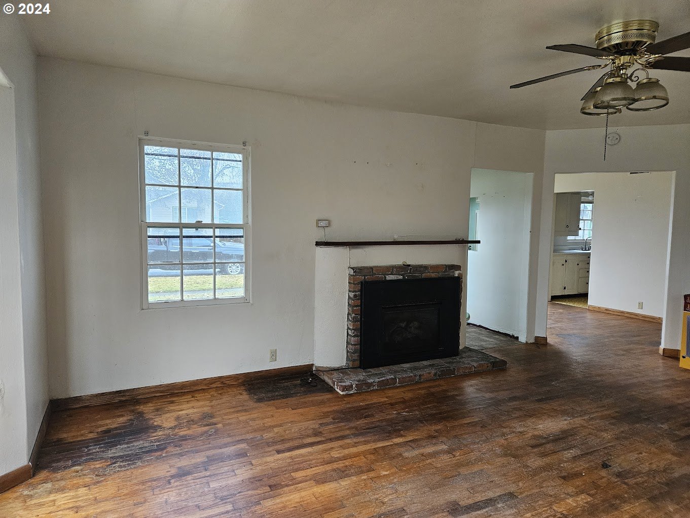 212 North Grant Street Goldendale, WA 98620 - Photo 7 of 15 an empty room with a fireplace and wooden floor