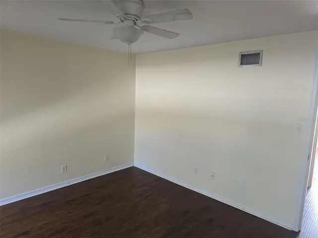 an empty room with wooden floor and fan
