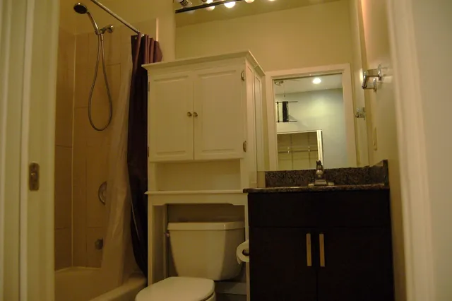 a bathroom with a granite countertop sink toilet and shower