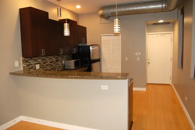 a kitchen with kitchen island granite countertop a refrigerator and a sink