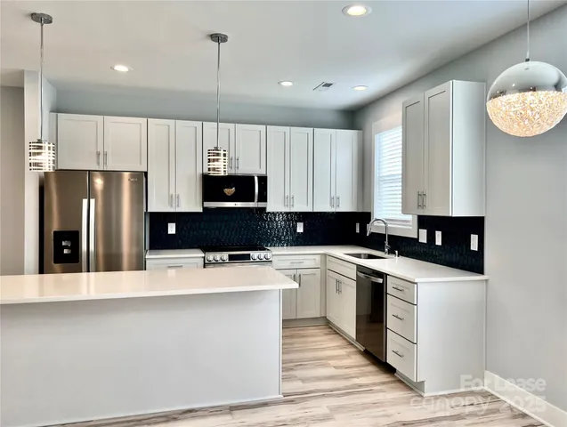 a kitchen with stainless steel appliances a stove a sink a refrigerator and white cabinets