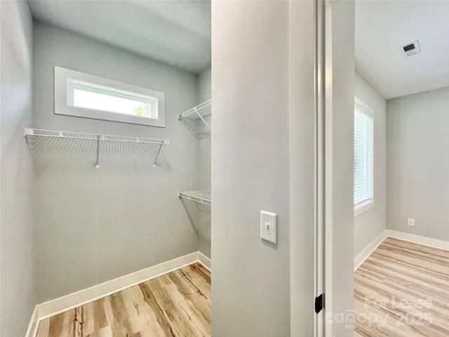 a view of a hallway with wooden floor and a bathroom