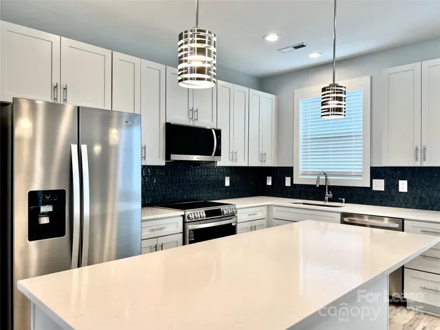 a kitchen with stainless steel appliances granite countertop a sink a stove and a refrigerator