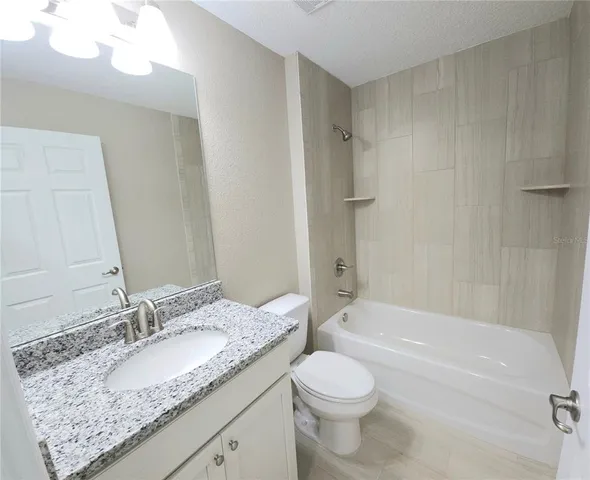 a bathroom with a granite countertop sink toilet and shower