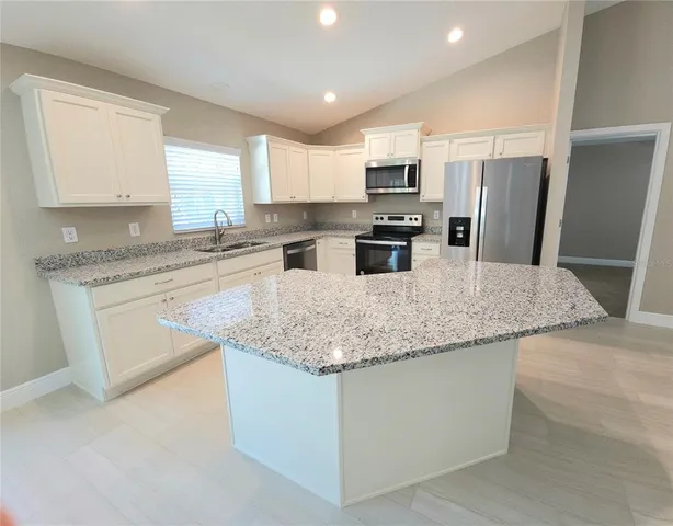 a kitchen with stainless steel appliances granite countertop a sink dishwasher stove top oven and refrigerator