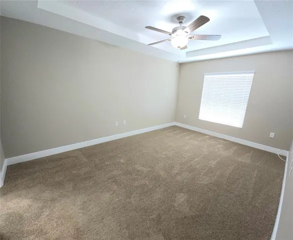 an empty room with a chandelier fan and windows