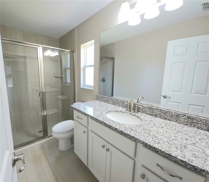 7794 North Keystone Drive Citrus Springs, FL 34433 - Photo 8 of 14 a bathroom with a granite countertop sink a toilet a mirror and shower