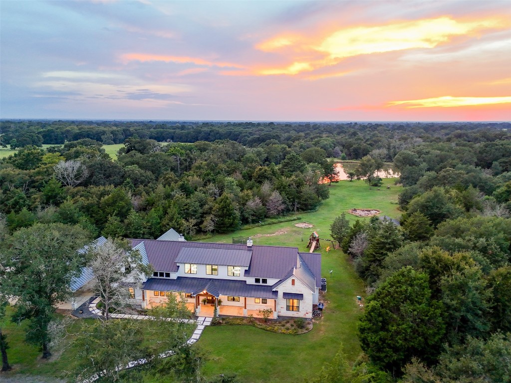 Dusk aerial captures the home and pond together, with vibrant skies adding to the property’s appeal.