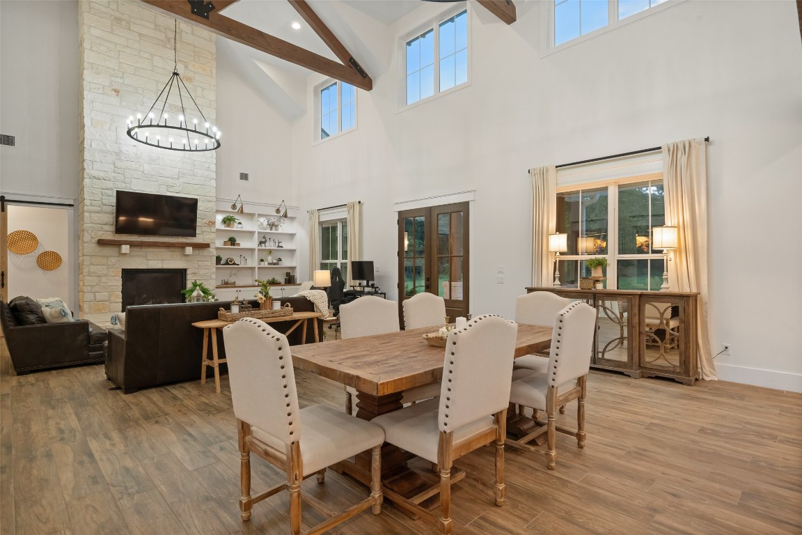 27201 Double Culvert Road Hempstead, TX 77445 - Photo 16 of 49 Open dining and living view with vaulted ceilings, wood beams, and seamless flow toward the stone fireplace centerpiece.