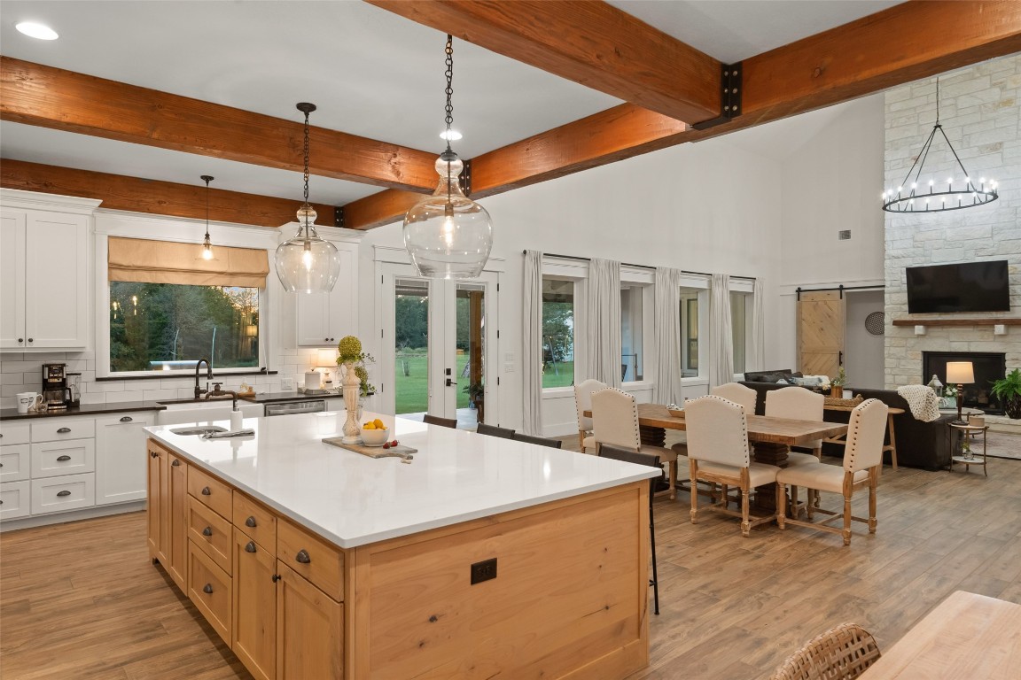27201 Double Culvert Road Hempstead, TX 77445 - Photo 17 of 49 Kitchen island with quartz surface stands central to the space, offering prep sink and seating with a backdrop of beams and windows.