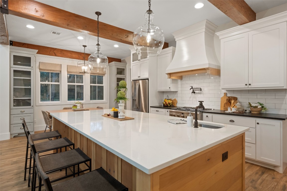 27201 Double Culvert Road Hempstead, TX 77445 - Photo 19 of 49 Kitchen island angle with quartz surface, veggie prep sink, pendant lighting, and sightlines to breakfast and living areas.