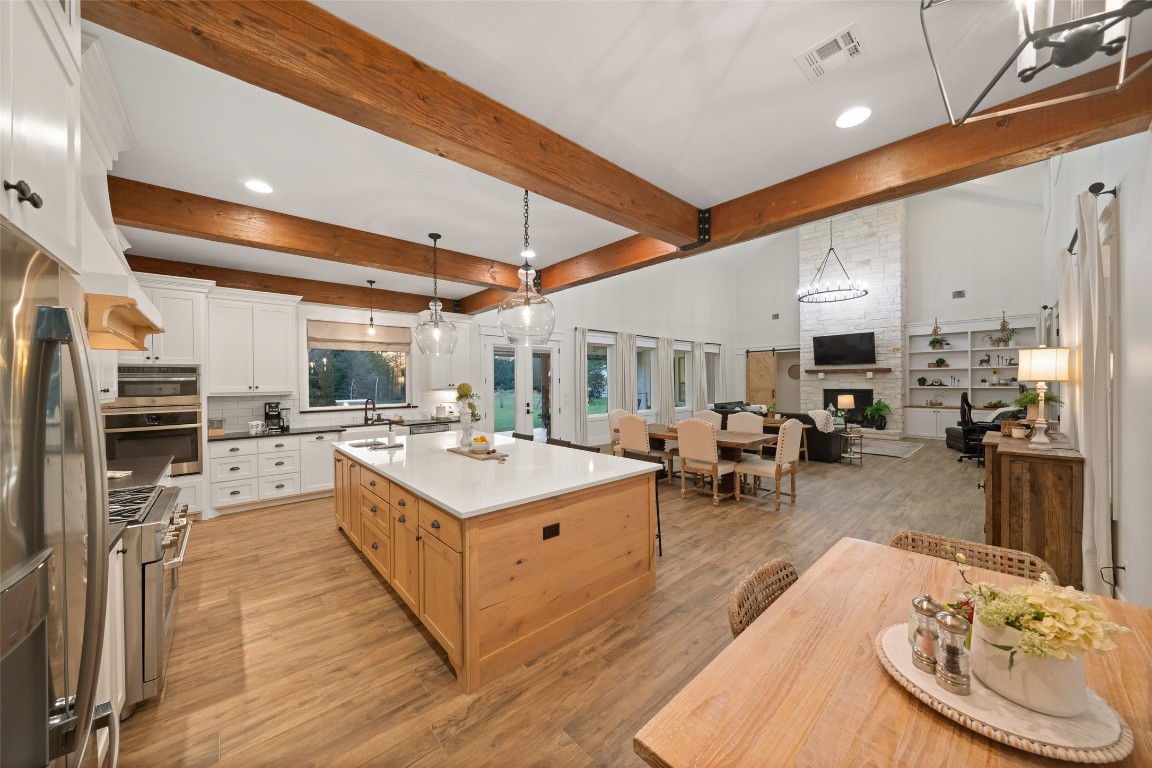 27201 Double Culvert Road Hempstead, TX 77445 - Photo 20 of 49 Expansive view of the kitchen flowing into the living room, showcasing exposed beams, pendant lighting, and seamless open design.