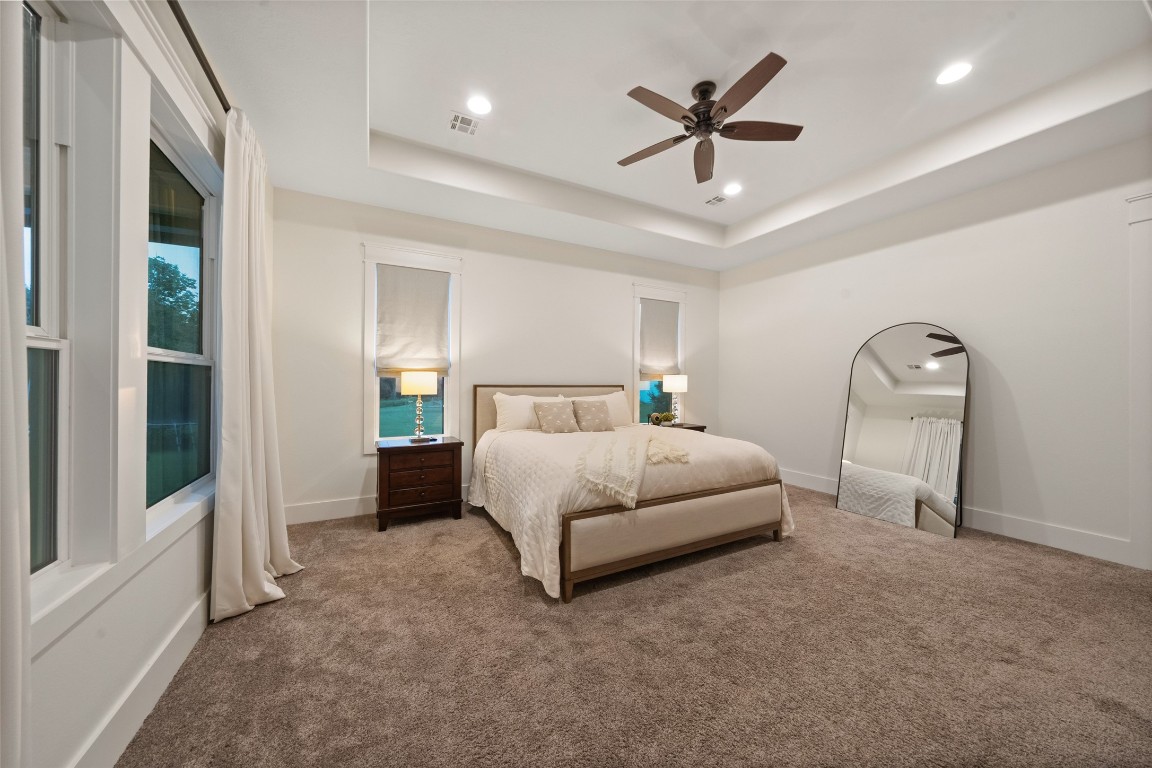 27201 Double Culvert Road Hempstead, TX 77445 - Photo 27 of 49 Primary bedroom features a tray ceiling with recessed lighting, double windows, and serene neutral finishes.