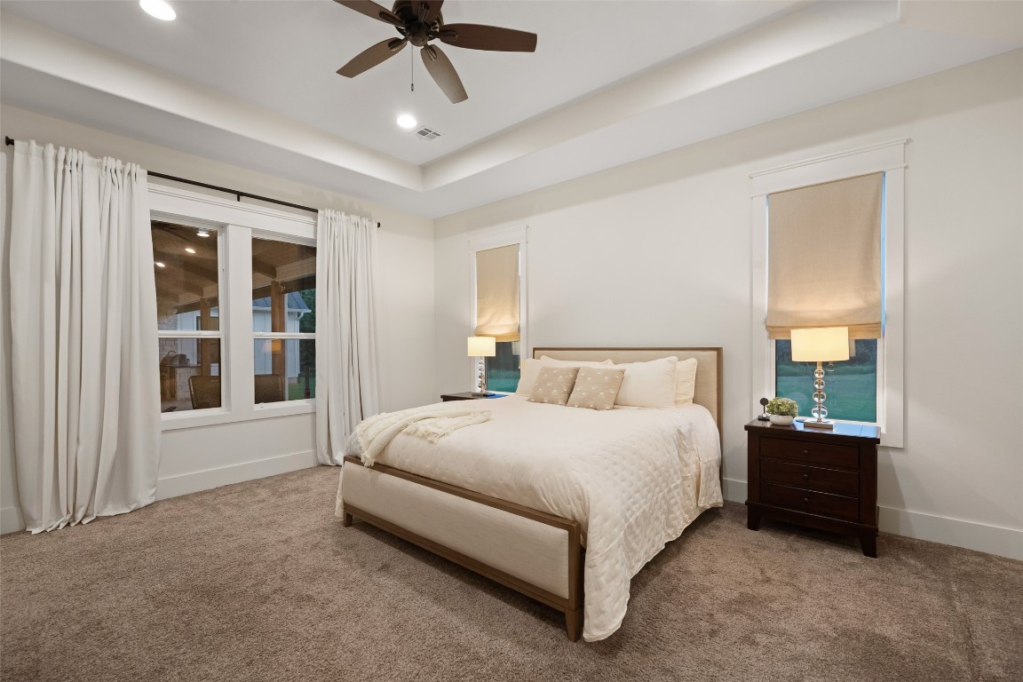 27201 Double Culvert Road Hempstead, TX 77445 - Photo 28 of 49 The serene primary suite features a tray ceiling, neutral tones, and oversized windows with elegant drapery. Plush carpet enhances comfort and warmth.