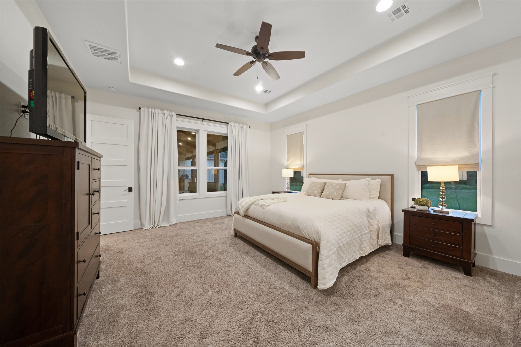 27201 Double Culvert Road Hempstead, TX 77445 - Photo 30 of 49 Owner’s suite captured from another angle, highlighting its generous proportions, tray ceiling, and oversized windows dressed with drapes.