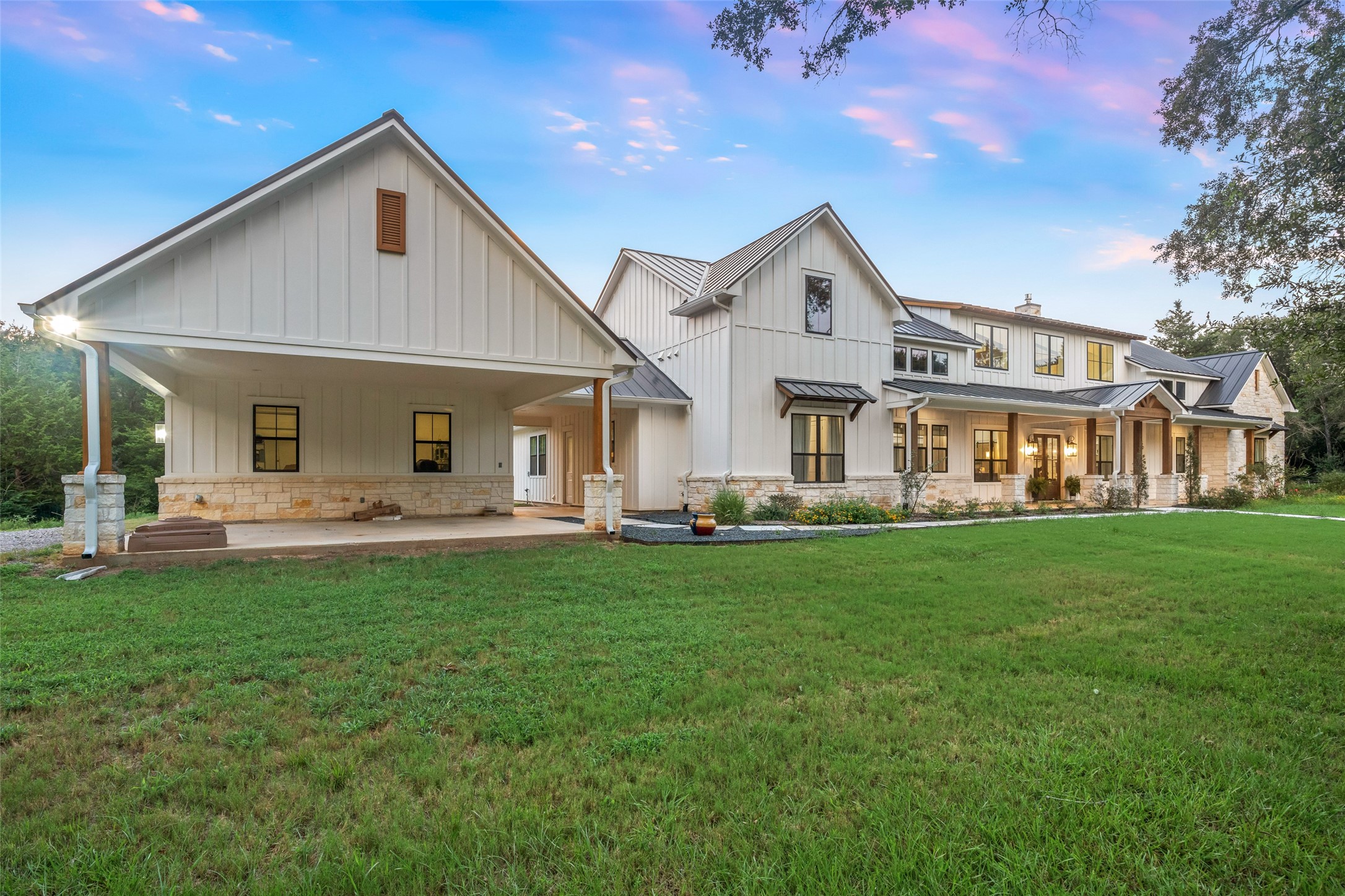 27201 Double Culvert Road Hempstead, TX 77445 - Photo 40 of 49 Exterior angle showing porte cochère, standing seam metal roof, and stone accents across the farmhouse elevation.