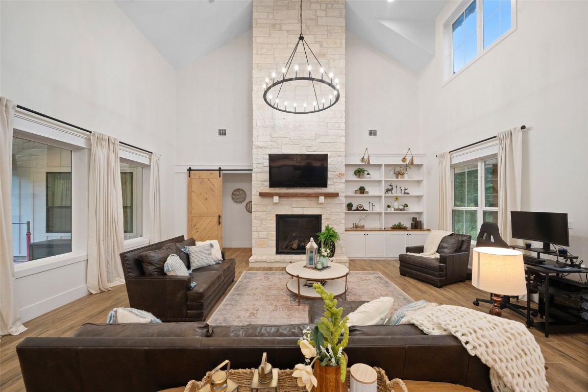27201 Double Culvert Road Hempstead, TX 77445 - Photo 5 of 49 Soaring vaulted ceilings with wood beams frame the living room, anchored by a striking stone fireplace and custom built-ins. Large windows with pleated shades fill the space with natural light.