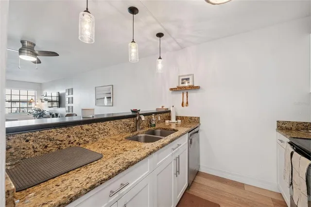 a kitchen with granite countertop a sink a counter and cabinets