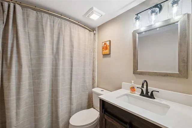 a bathroom with a sink a toilet and shower curtain