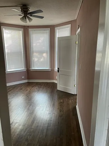 an empty room with wooden floor fan and windows